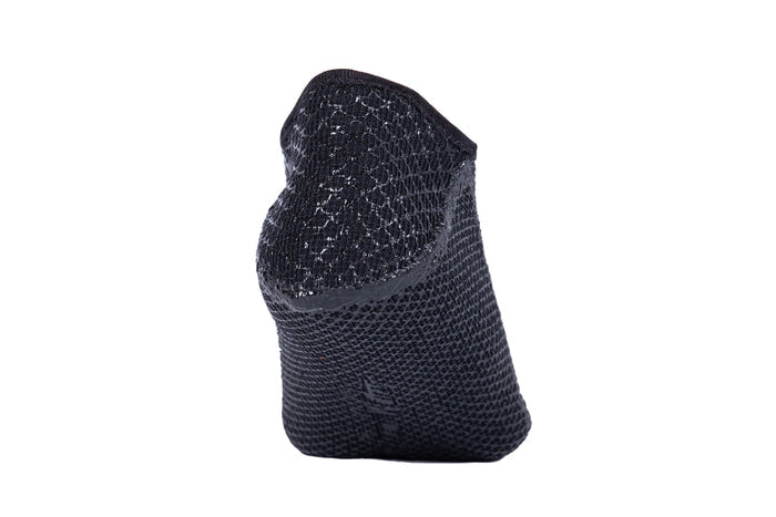 Waihana Essentials black neoprene short dive sock shown at an angle on a white background, highlighting the open-mesh upper texture and structured neoprene sole.
