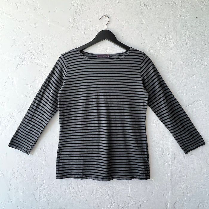 Black and gray striped long-sleeve shirt on a hanger against a white wall