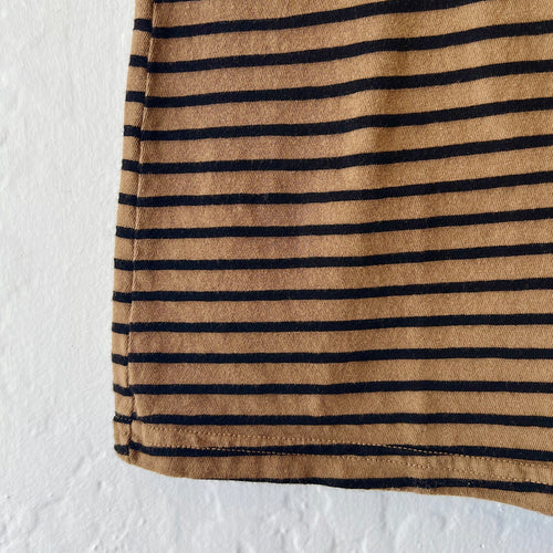 Close-up of a brown fabric with black stripes on a textured white background