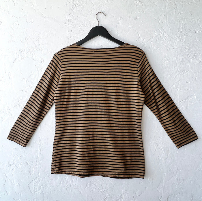 Brown and black striped long-sleeve shirt on a hanger against a white wall, viewed from behind
