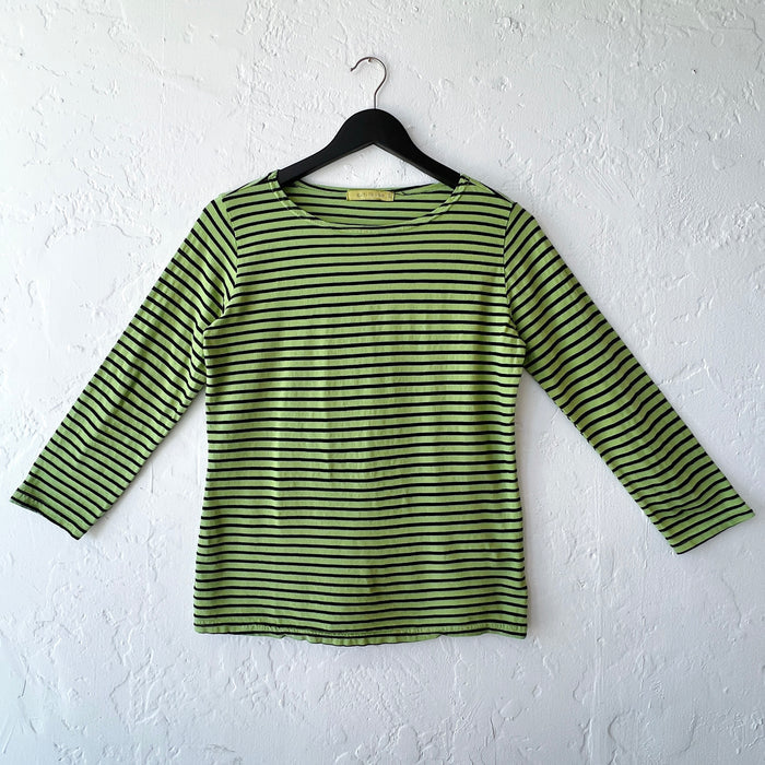 Green and black striped long-sleeve shirt on a hanger against a white wall