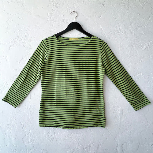 Green and black striped long-sleeve shirt on a hanger against a white wall