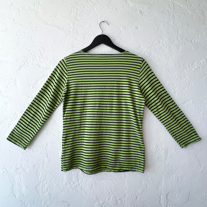 Green and black striped shirt on a hanger against a white wall