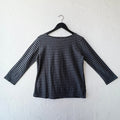 Black and gray striped long-sleeve shirt on a hanger against a white wall