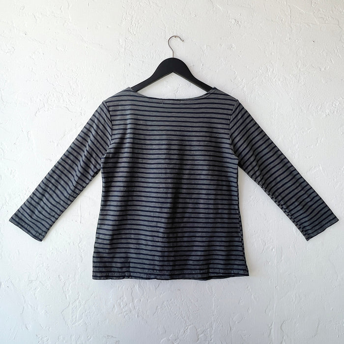 Striped long-sleeve shirt on a hanger against a white wall, viewed from the back