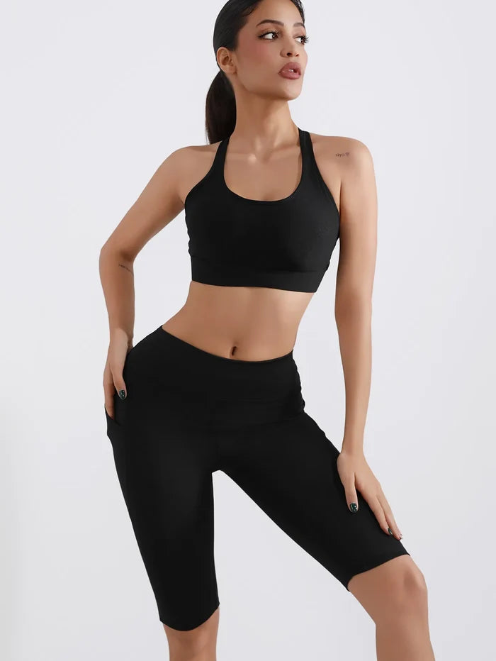 Woman wearing a black sports bra and capri leggings on a white background