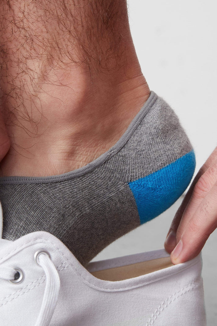 Side view of a man putting on a shoe and wearing Everyday No Show Sock in Grey Heather