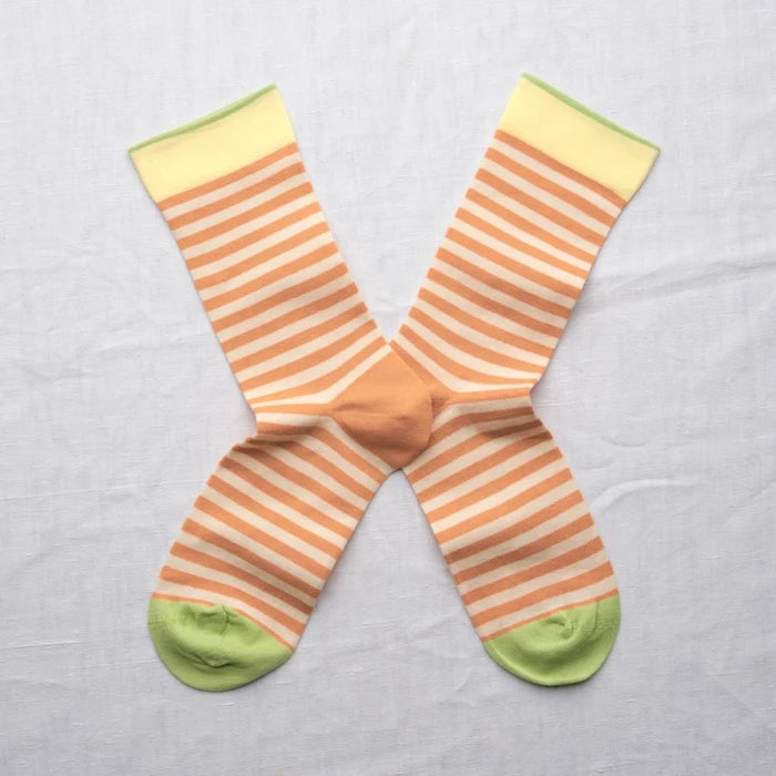 Adobe Striped Peach socks by Bonne Maison — fine horizontal peach and cream stripe cotton crew with yellow cuff and lime green heel and toe, flat lay pair crossed on a white linen background