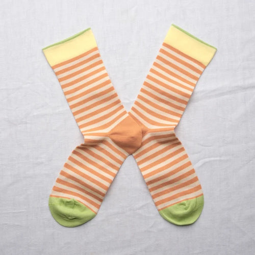 Adobe Striped Peach socks by Bonne Maison — fine horizontal peach and cream stripe cotton crew with yellow cuff and lime green heel and toe, flat lay pair crossed on a white linen background