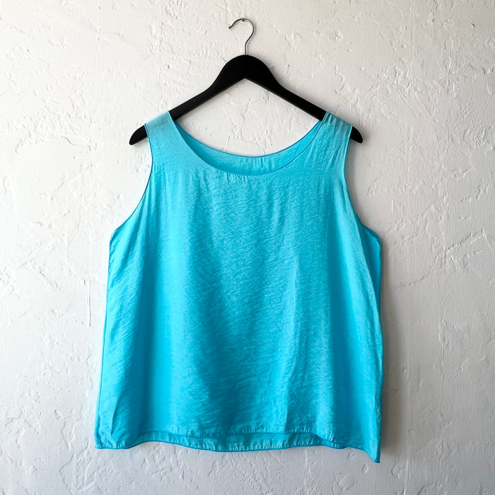 Blue tank top on a hanger against a white wall