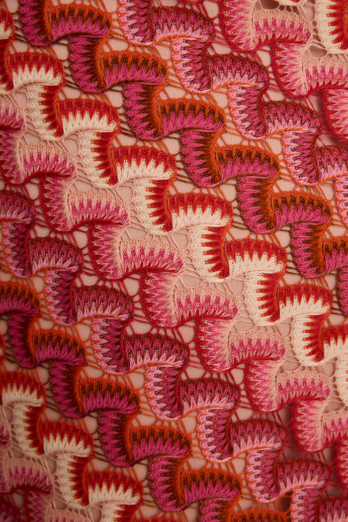 Close-up of pink and orange crochet knit skirt fabric, an open shell-stitch resort look.