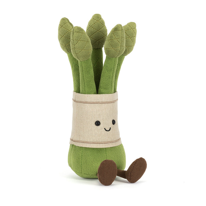 Jellycat Amuseables Asparagus plush toy at a slight angle showing the green stalks, cream linen band with embroidered smile, and one brown corduroy foot extended to the side, on a white background