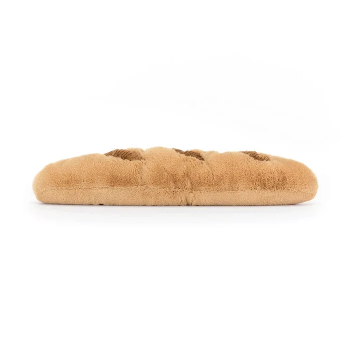 Jellycat Amuseables Baguette — top-down side view of the full-length plush baguette showing the golden-brown textured surface and corduroy score marks, lying flat on a white background