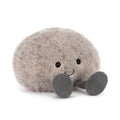 Plush toy resembling a round grey stone with a smiling face and grey legs on a white background
