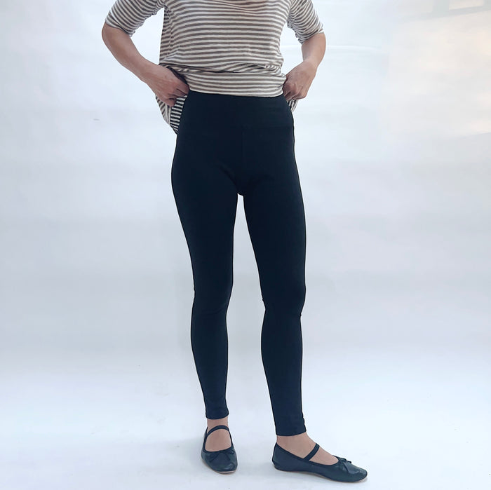 Person wearing black leggings and a striped shirt on a white background