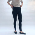 Person wearing black leggings and a striped shirt on a white background