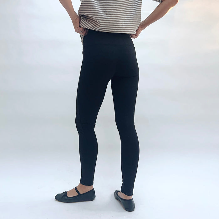 Person wearing black leggings on a white background, viewed from the back