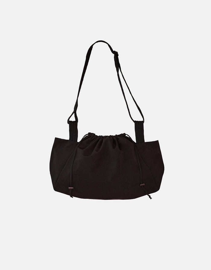 Black unisex shoulder bag with a minimalist design featuring a soft, gathered top closure and adjustable strap, combining timeless elegance with functional craftsmanship.