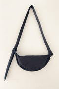 Minimalist unisex denim crossbody bag with asymmetrical volume and a tied strap, crafted with understated elegance and high-quality French design.