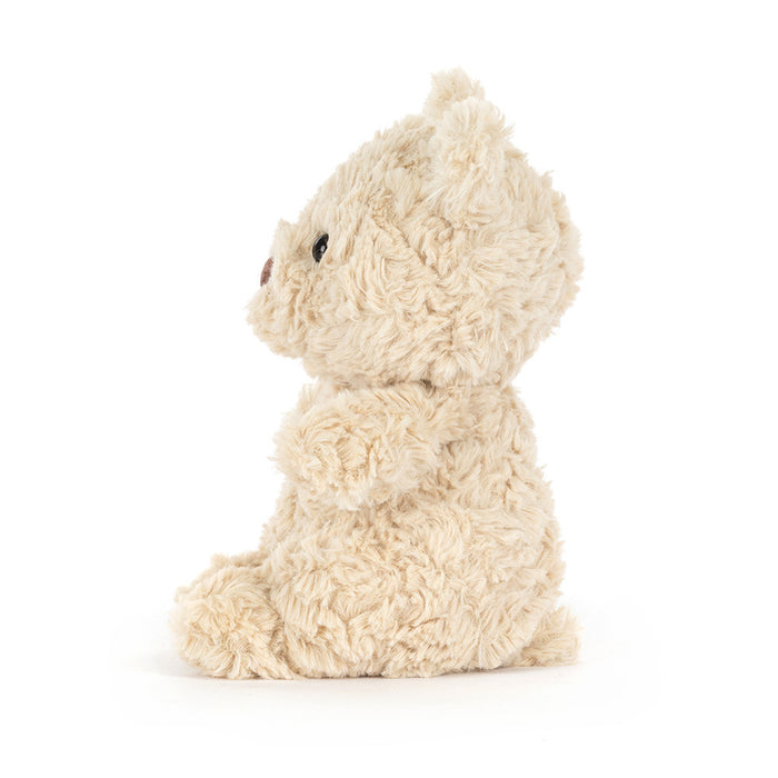 Side profile of Jellycat Bartholomew Bear Junior showing curly cream fur texture and rounded seated silhouette on a white background