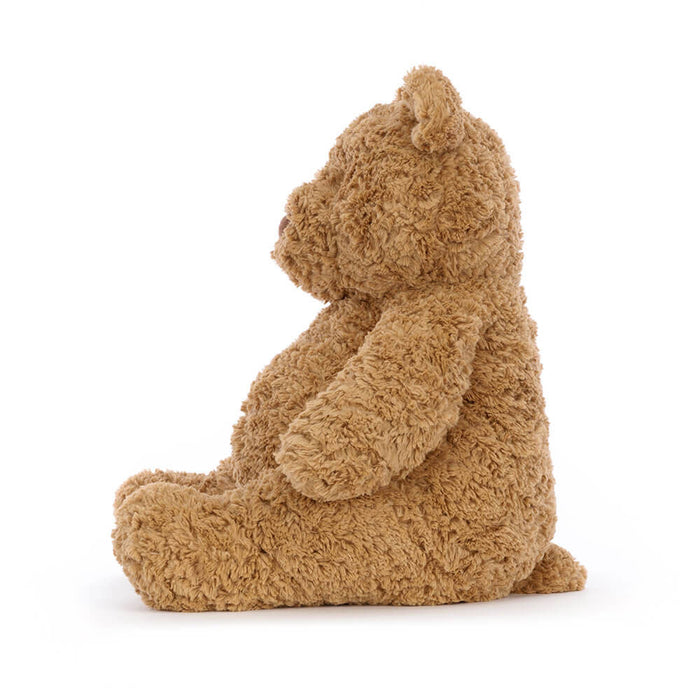 Brown teddy bear sitting on a white background, viewed from the side