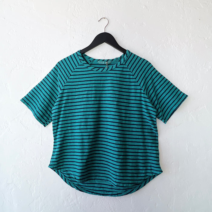 Teal and navy striped shirt on a hanger against a white wall
