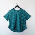 Teal and navy striped shirt on a hanger against a white wall