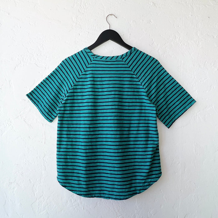 Teal and navy striped shirt on a hanger against a white wall, viewed from the back