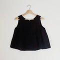 Cropped black linen tank top displayed on a wooden hanger against a white background.
