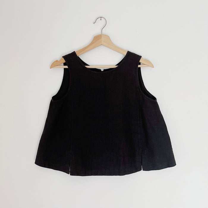 Cropped black linen tank top displayed on a wooden hanger against a white background.