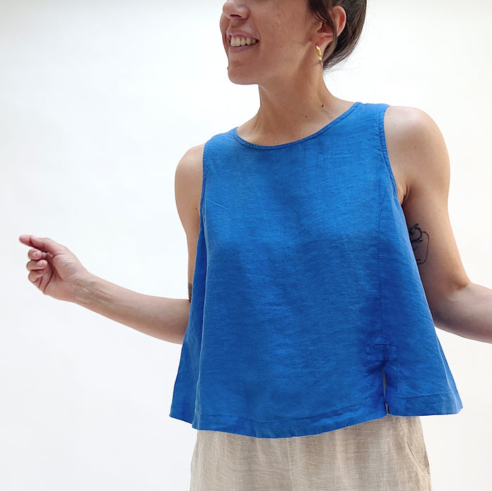 A close up shot of a person in a bright cobalt blue linen tank with her arms out at her sides