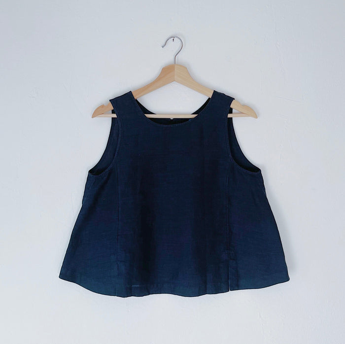 A navy linen tank top with buttons down the back and side slits, displayed on a hanger against a white background.