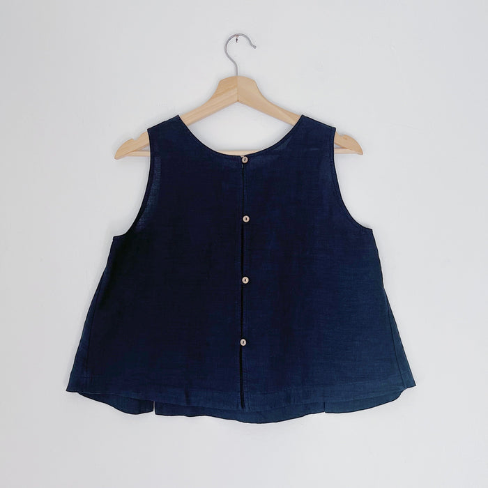 A navy linen tank top with buttons down the back and side slits, displayed on a hanger against a white background.