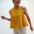 Person wearing a mustard yellow sleeveless top against a white background