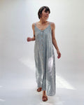 Woman wearing a long, striped linen dress in white and grey on a white background.