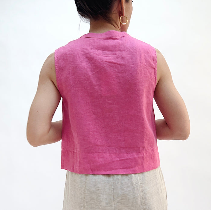 Person seen from behind wearing a pink sleeveless top on a white background