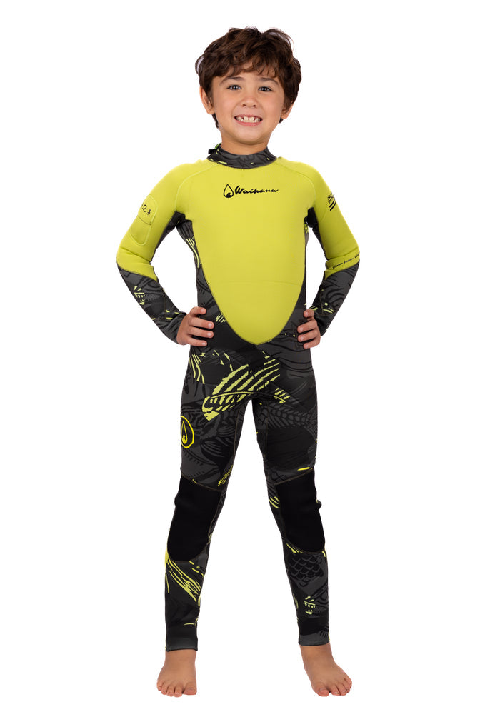 Smiling child wearing the Waihana Children's Lime Fishbone Steamer wetsuit in bright lime green and dark grey fishbone-patterned neoprene, standing confidently with hands on hips against a white studio background.