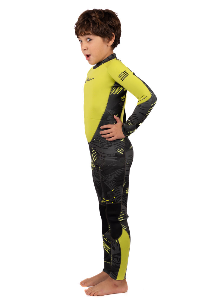 Young boy modeling the Waihana Children's Lime Fishbone Steamer full wetsuit in yellow-green and dark grey graphic print, shown from a side angle on a white background.