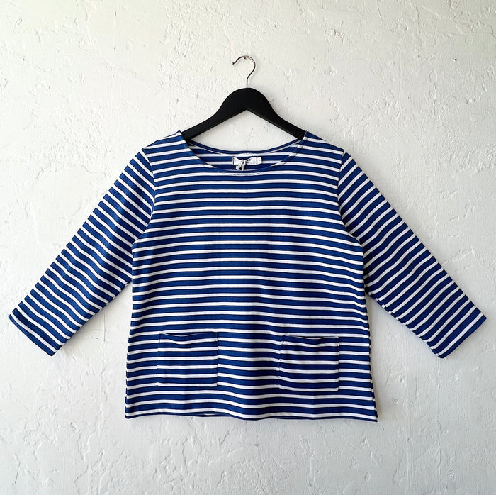Blue and white striped shirt on a hanger against a white wall