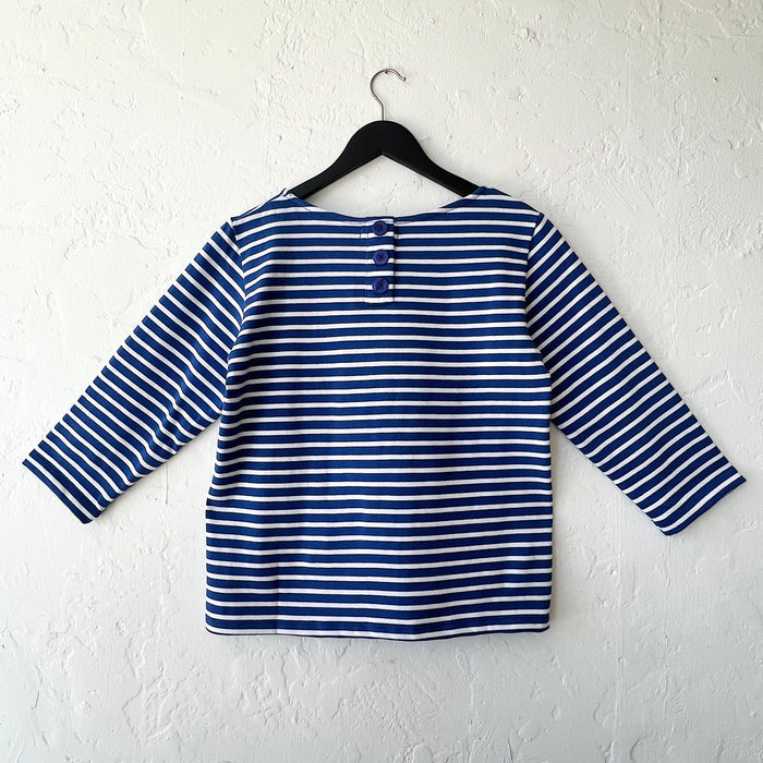 Blue and white striped shirt on a hanger against a white wall