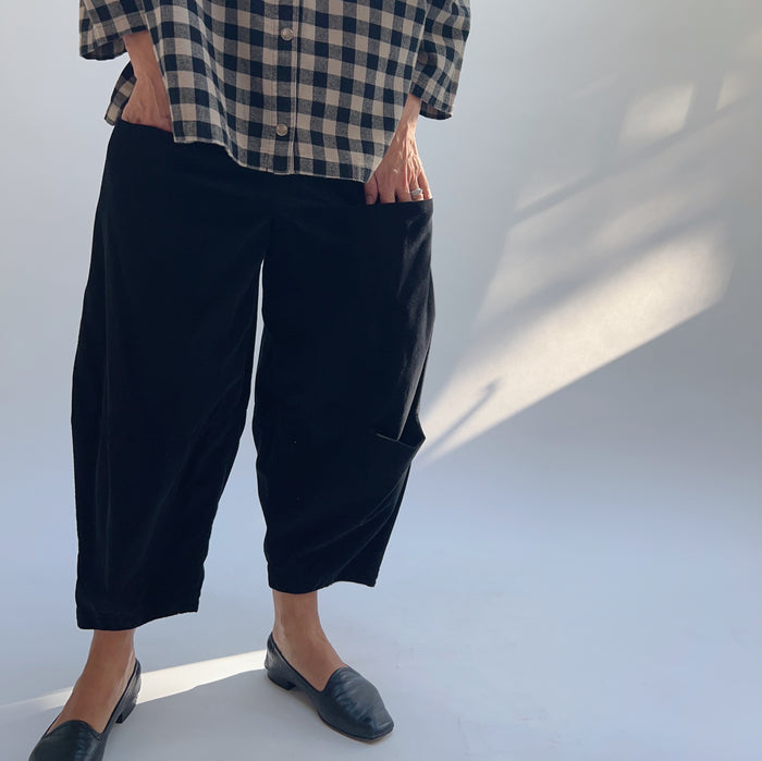 Model with hand in side pocket of black corduroy pant, highlighting the functional pocket placement and cropped length