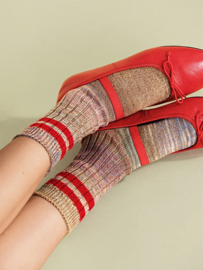 Cosmic Space Dye Varsity Crew socks in Ruby — multicolor space dye ribbed crew with bold red varsity stripes, worn with red leather bow ballet flats on a sage green background