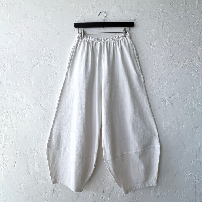 Pacific Cotton cream Oliver pant on hanger, front view showing elastic waistband, wide balloon-leg silhouette, patch panels at hem, and full length