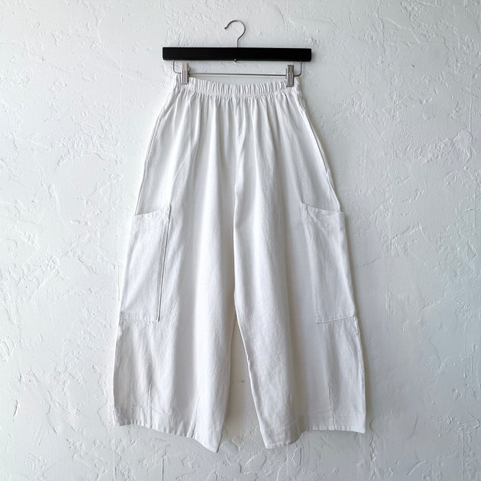 White wide-leg pants on a hanger against a white wall