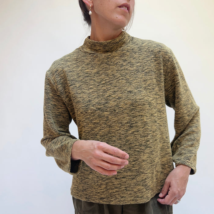 Person wearing a green marled sweater against a plain background