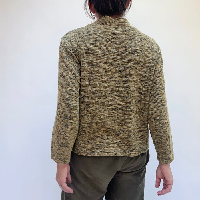 Person wearing a green and brown speckled jacket against a white background, view from behind.