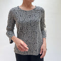 Person wearing a black and white patterned top against a plain background