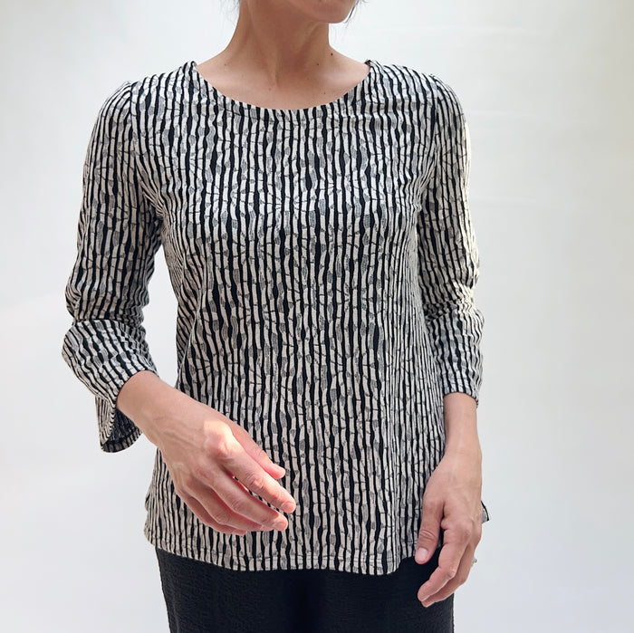 Person wearing a black and white patterned top against a plain background