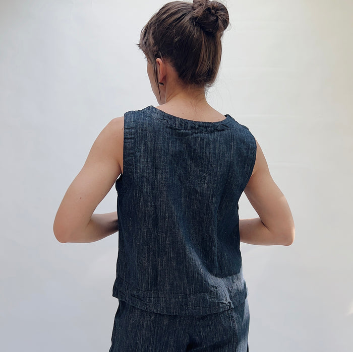 Person wearing a sleeveless denim top against a plain background
