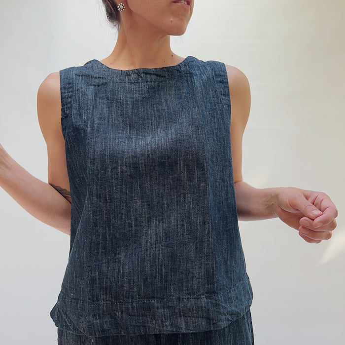 Person wearing a sleeveless denim top against a plain background